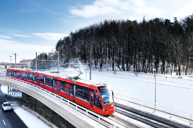 The tram Bernmobil equipped with a transmission exchange unit drives through the snowy landscape of Switzerland<BR> 