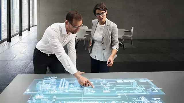 A man and woman work together on a visual representation of a paper mill.